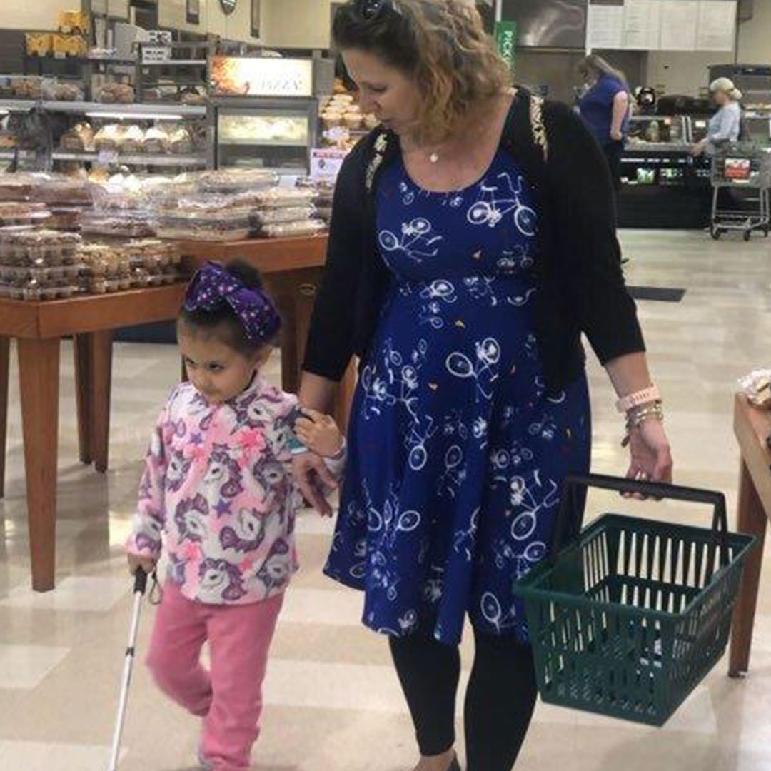 A mother walks with her young visually impaired daughter through a supermarket.