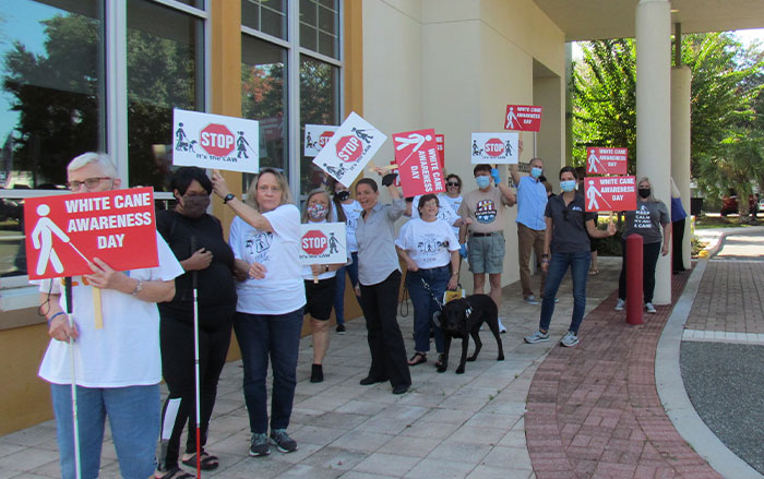 A group walks with signs on White Cane Awareness Day.