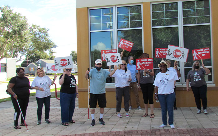 A group holds up signs on White Cane Awareness Day.